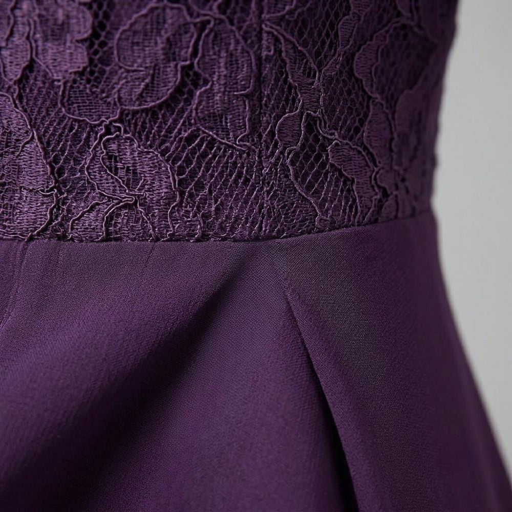 Detalhe de vestido midi roxo com corpete em renda floral e saia fluida de poliéster com pregas elegantes.