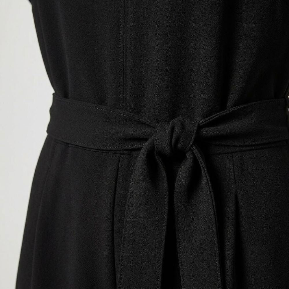 Macacão feminino preto elegante com cinto ajustável de laço na cintura e corte fluido em tecido de poliéster.
