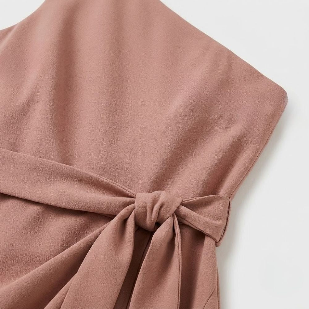 Vestido curto de festa rosa em crepe com decote assimétrico e detalhe de laço na cintura.