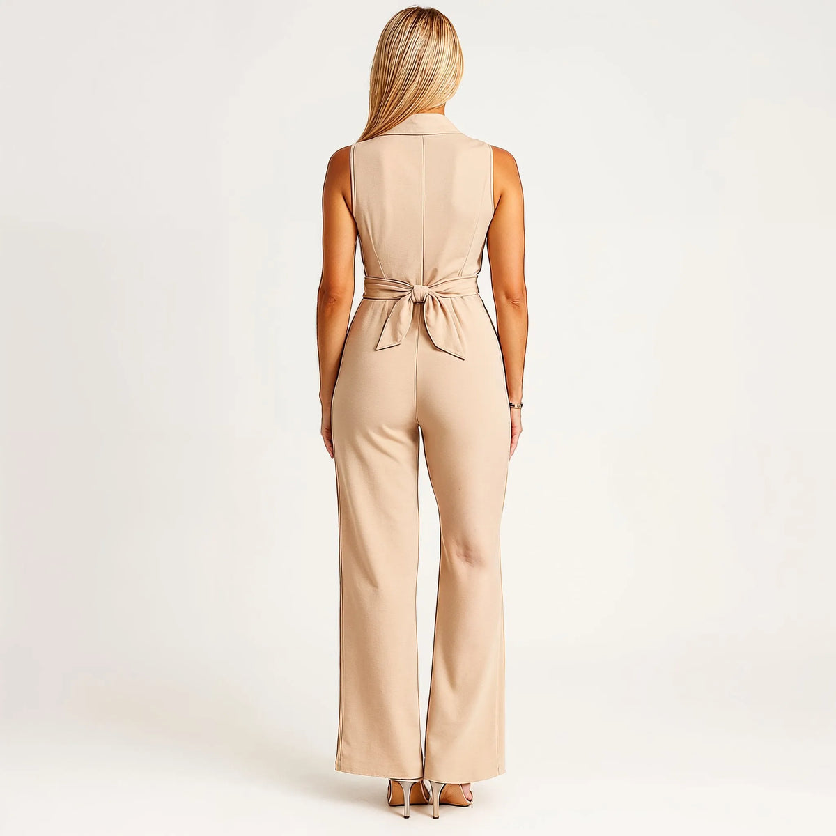 Macacão feminino bege de perna larga, sem mangas, com detalhe de laço na cintura e corte elegante em tecido fluido.